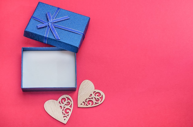 Open blue box on a red background with an empty place for a gift with hearts with copy space, Gifts for men