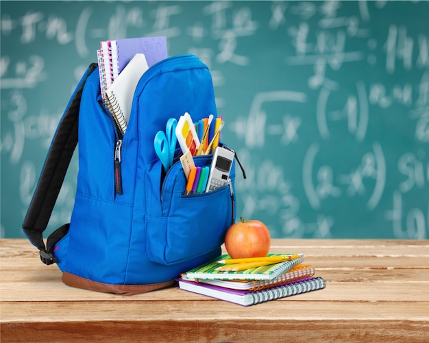 Open blue school backpack and notebook with apple