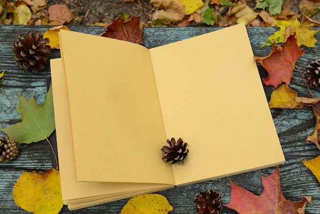 Open boek en herfstbladeren op een houten tafel buiten Leeg notitieblok met pagina's gemaakt in ambachtelijk papier