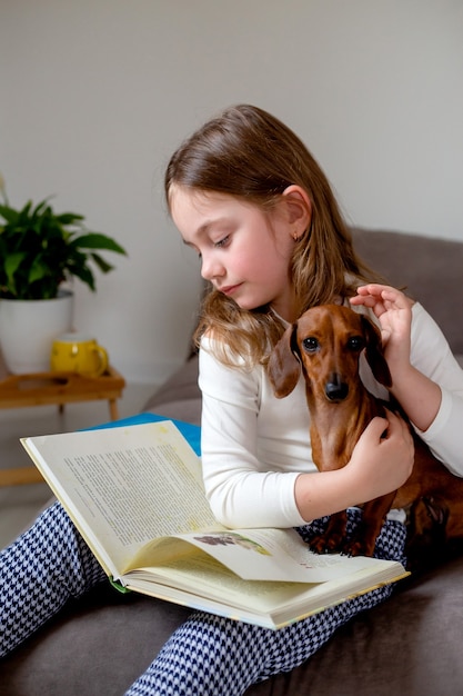 Open boek ligt op de schoot van het meisje het kind speelt op school en leert de hond lezen