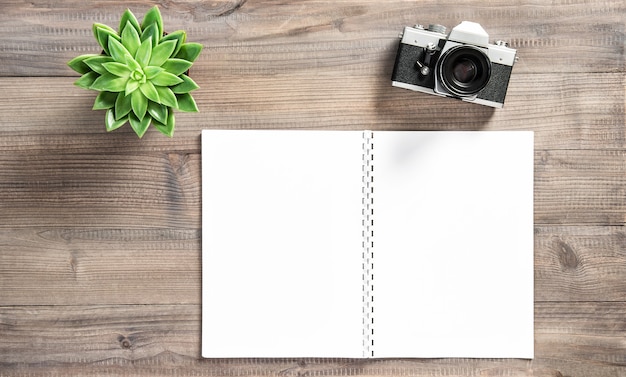 Open boek, vintage fotocamera, sappig op houten tafel. Bureau plat gelegd