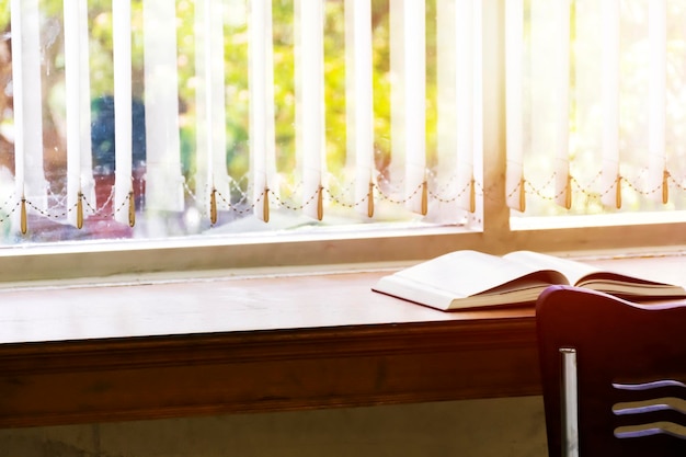 Open boek wordt op tafel bij het raam gelegdLaat een licht in het boek branden Lezen is de beste manier om te lerenxAVerbeter kennis en verbeeldingEr wacht een goede toekomst op je