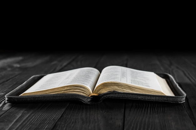 Открытая книга Библия на черном деревянном