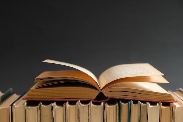 Open book on black background, hardback books on wooden table. Education and learning.