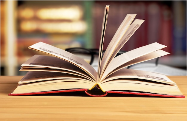 Open book and black glass on bokeh background