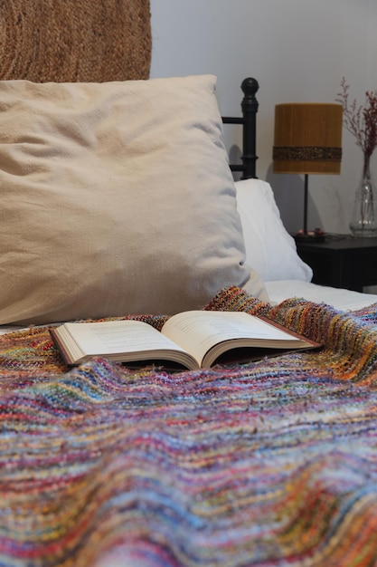 Open book on colorful blanket on bed