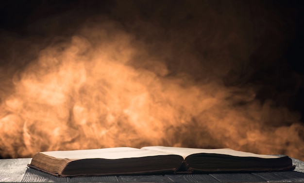 Open book on the desk in a backlight with smoke on the background