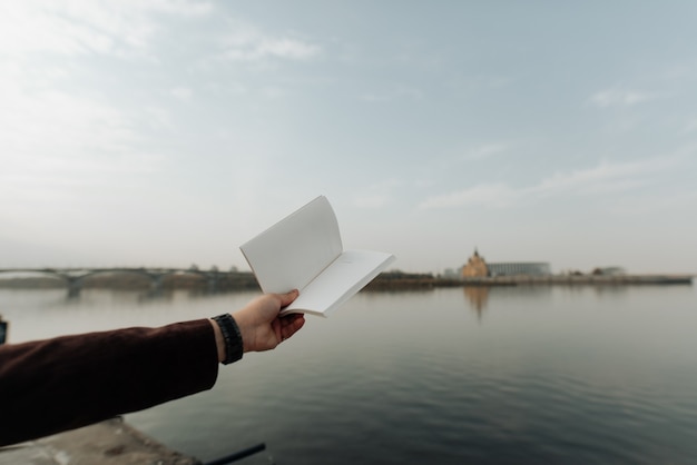 Open book in hands on a background of water close-up