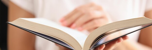 Open book in hands of woman closeup shallow depth of field concept of education learning and