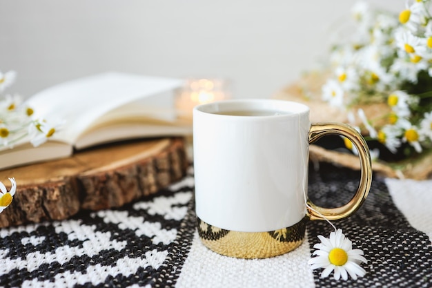 Open book herbal chamomile tea cup on wooden table reading and morning relax concept