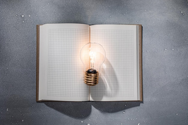 Photo an open book illuminated by a light bulb education and knowledge concept