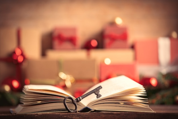 Open book and key with Christmas gifts on background