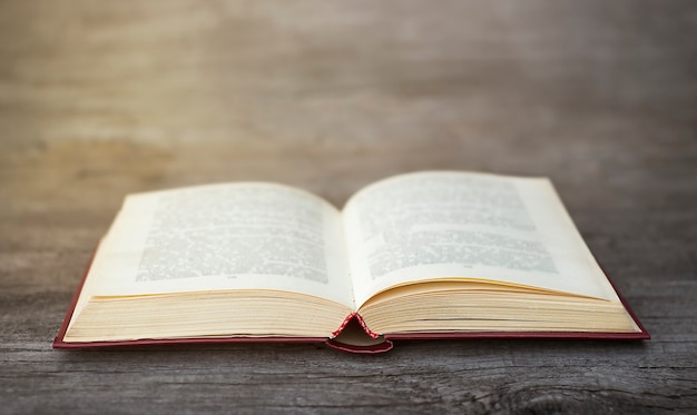 Open book lies on a gray wooden background closeup in sunbeams