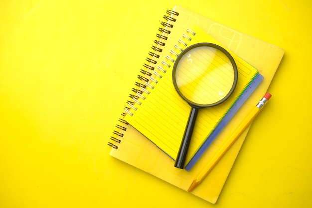 Open book and magnifying glass on yellow