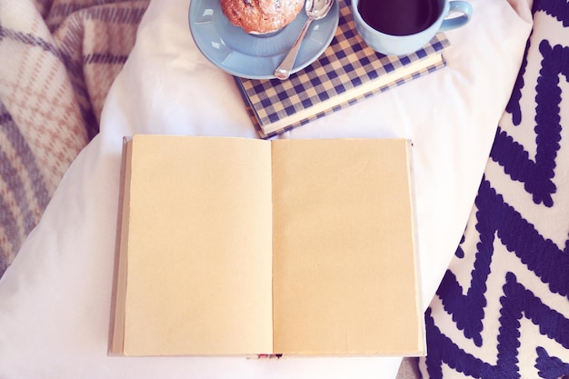 Open book plaid and coffee on sofa Top view