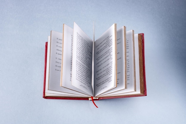 An open book in a red cover on a blue background selective focus