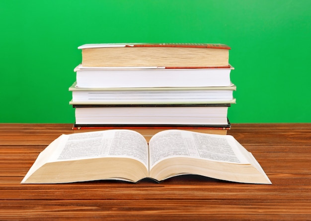 Open book on a stack of books on a table.