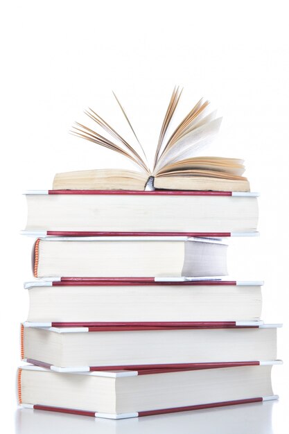 Open book on stack of books. On a white wall