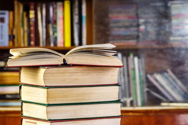 An open book on a stack in front of a bookcase. Learning concept