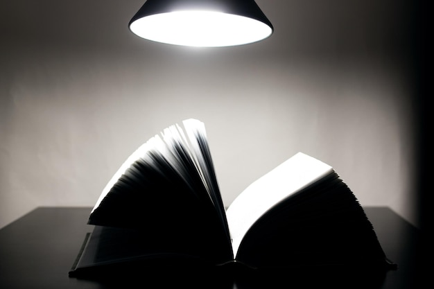 Open book on table lamp in dark
