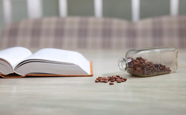 Open book on white table and coffee grains, education concept