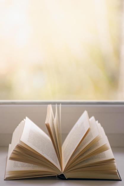 Open book on a window sill illuminated by sunlight