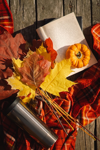 写真 木製の背景に格子縞の紅葉のオレンジ色のカボチャの花束で本を開く