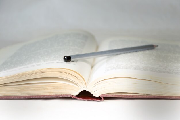 Open book with a pencil, illuminated by a ray of light.