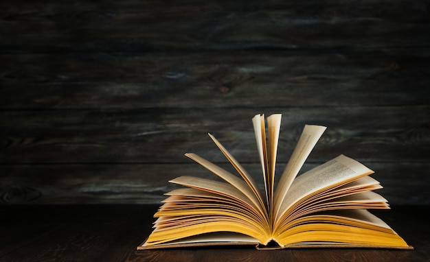 Open book with yellow pages on a wooden background copy space. Old textbook.