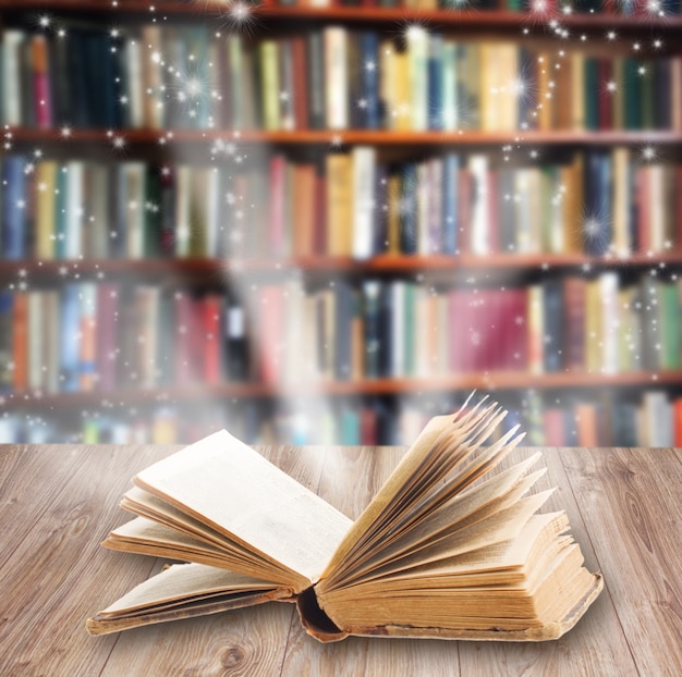 Открытая книга на деревянной книжной полке с волшебным светом