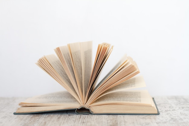 Open book on a wooden surface against the background of a white wall