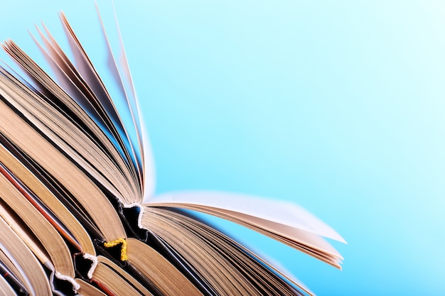 Open books are stacked on the desk on blue. Difficult homework at school, a mountain of knowledge.