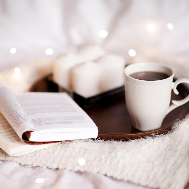 Open books candles and cup of tea on wooden tray in bed Good morning Leisure time