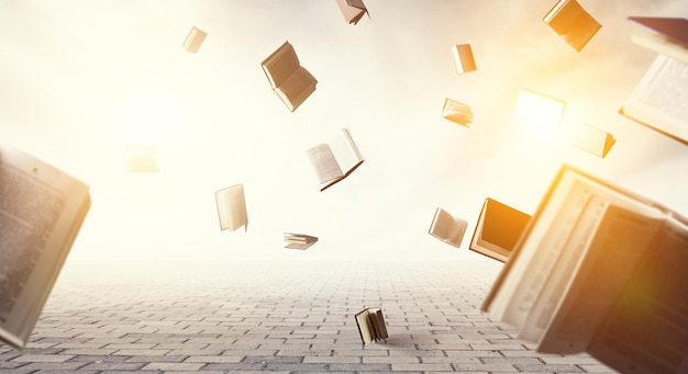 Open books flying around on light sky background and stone ground