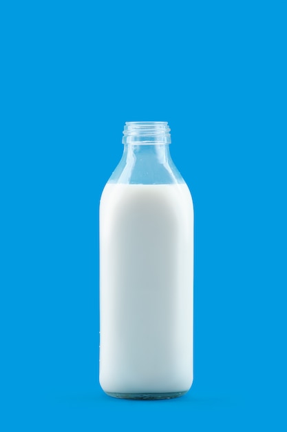 青色の背景に分離された牛乳の瓶を開く