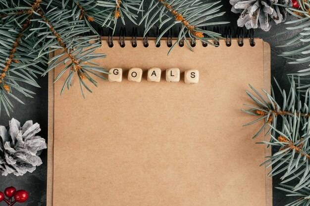 Open brown kraft paper folded notebook with Goals written on wooden cubes. Christmas and New Year. Top view. Copy space