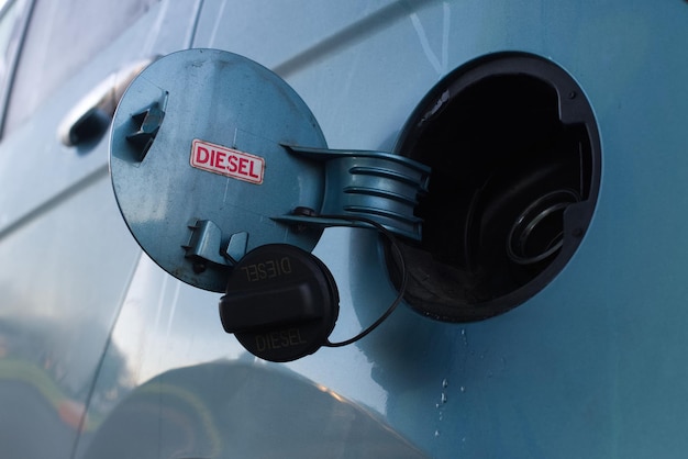 Открытая крышка топливного бака автомобиля с красным знаком для дизельного топлива под низким углом