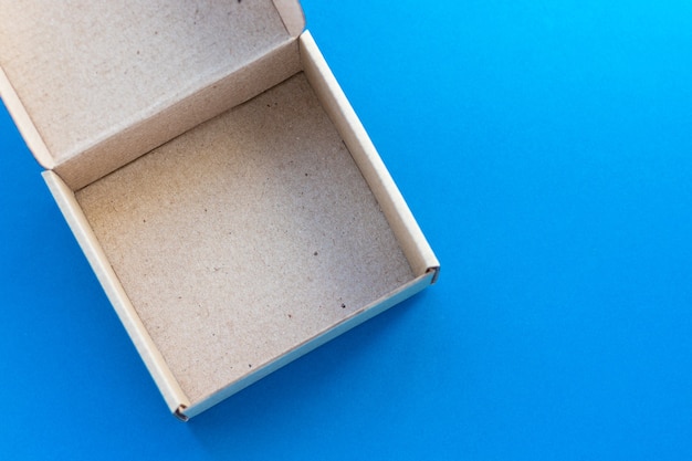 Open cardboard box on blue background. Eco-friendly parcel, packing. Top view, flat lay.