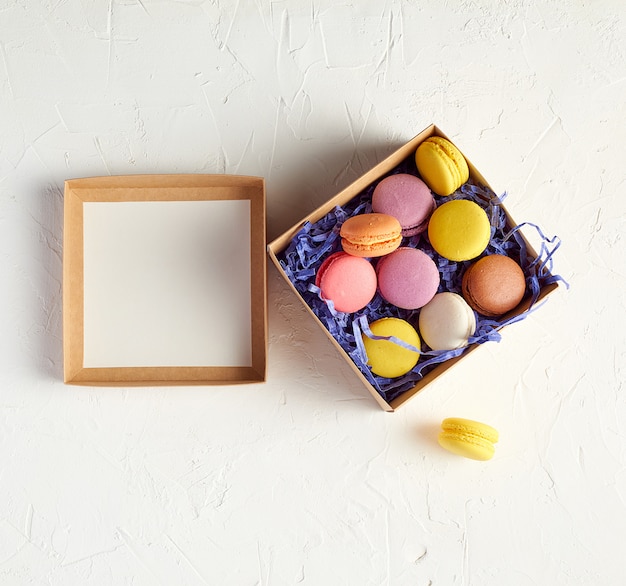 Open cardboard box with a baked dessert multi-colored round macarons