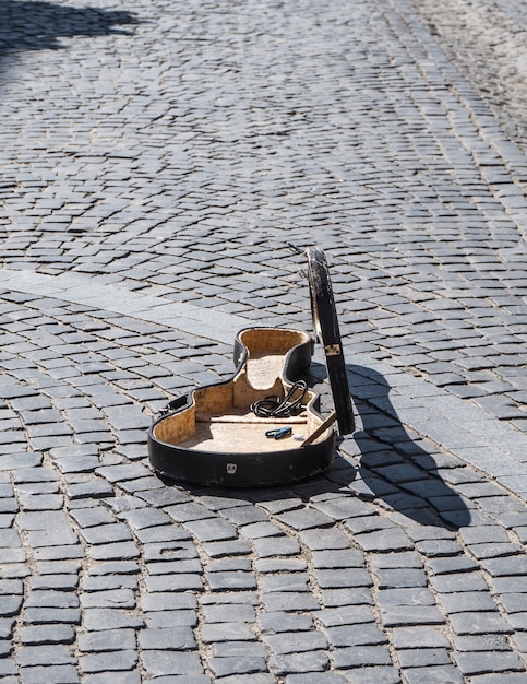 Open case of the cello on the old cobblestones