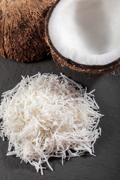 Open coconut in the middle on top of stone with coconut shavings and grated coconut.
