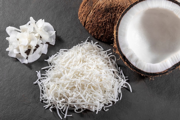 Open coconut in the middle on top of stone with coconut shavings and grated coconut.