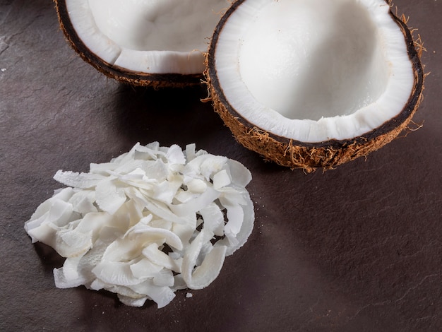 Open coconut in the middle on top of stone with coconut shavings.