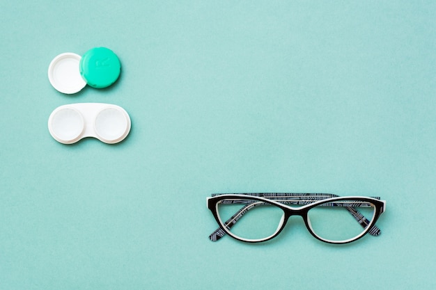 Open container with lenses and glasses green background