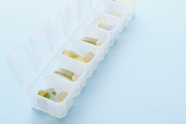 Open dagelijkse pillendoos met verschillende pillen op blauw.