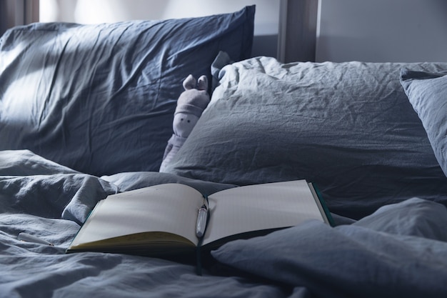 Diario aperto da scrivere sul letto con tessuti blu al chiaro di luna rituali serali per la salute mentale