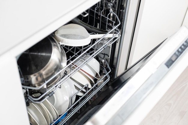 Open dishwasher with clean utensils in it.