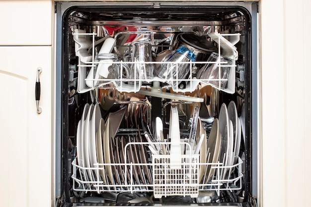 Open dishwasher with perfectly clean dishes after washing, front view.