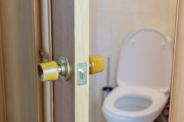 Open door to the toilet. wooden interior door handle with a\
simple lock. focus on the door.