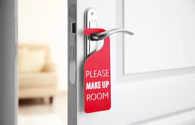 Open door with sign PLEASE MAKE UP ROOM on handle at hotel